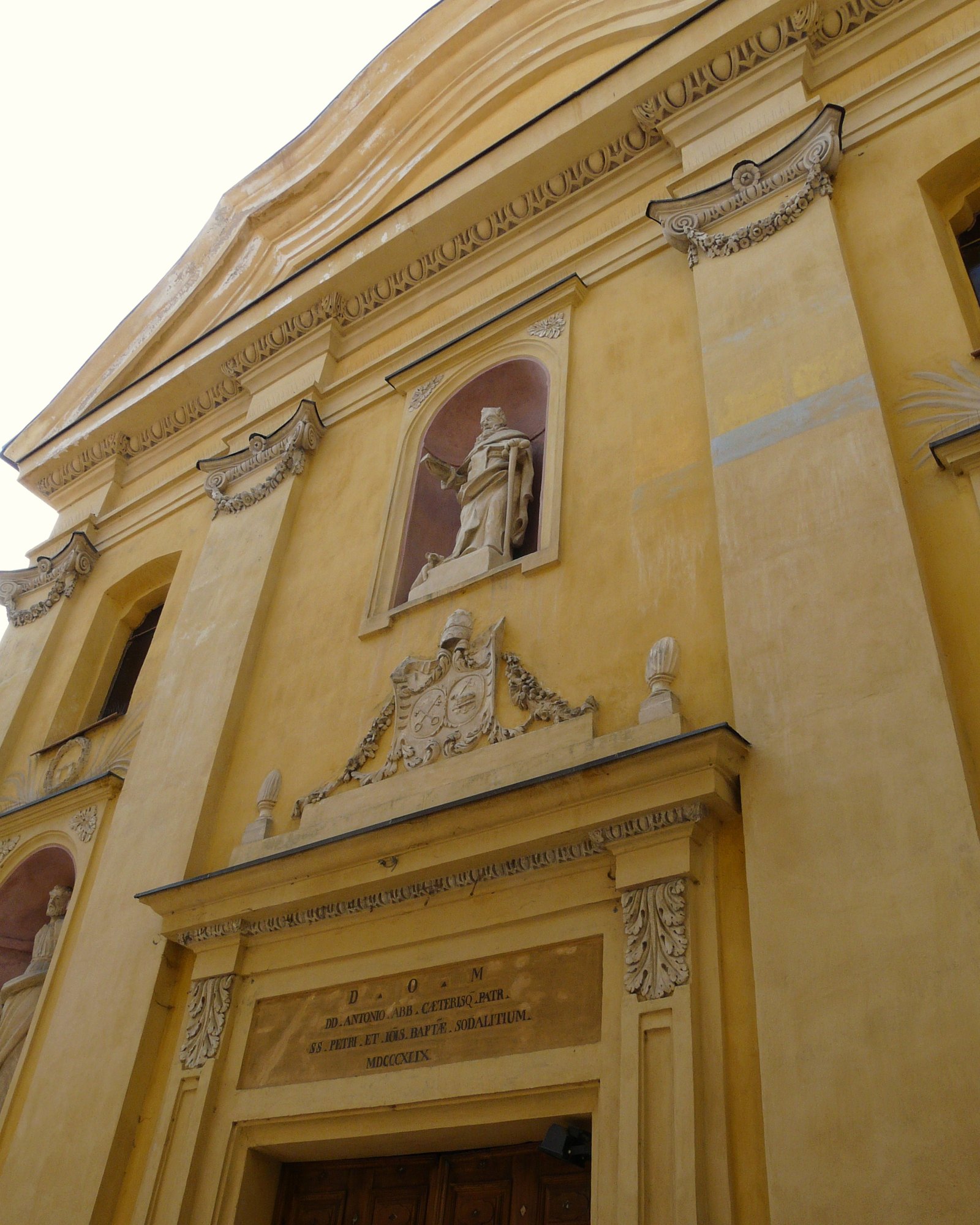 L'ordine superiore della facciata della chiesa di Sant'Antonio Abate, con la statua del santo nella nicchia e lo stemma sopra il portale